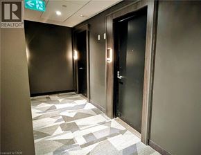Kitchener condo for rent - A hallway with a tiled floor and a green exit sign above the door.