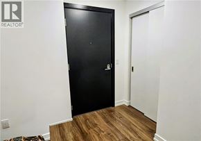 Kitchener condo for rent - A black door is in a white room with a wooden floor.