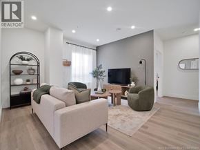 Moncton apartment for rent - A living room with a white couch, a green armchair, and a television.