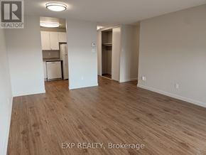 Ottawa multi-family for rent - A room with wooden flooring and a kitchen area in the background.