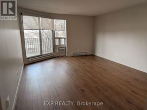 Ottawa multi-family for rent - A room with wooden flooring and a large window with a view of a fence and trees.