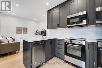Ottawa multi-family for rent - A modern kitchen with black cabinets and stainless steel appliances.