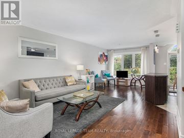 Ottawa townhouse for rent - A well-lit living room with a grey sofa and a glass coffee table.