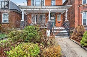 Hamilton apartment for rent - A red brick house with a white porch and a small front yard.