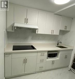 Toronto (Don Valley Village) apartment for rent - A kitchen with white cabinets and a black stove top.