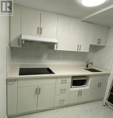 Toronto (Don Valley Village) apartment for rent - A kitchen with white cabinets and a black stove top.