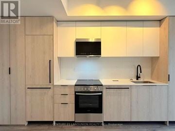 Toronto (Centennial Scarborough) condo for rent - A kitchen with wooden cabinets and a microwave above the stove.