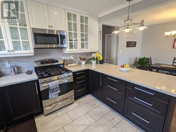 Ajax (South East) apartment for rent - A kitchen with black cabinets and a stove top oven.