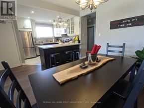 Ajax (South East) apartment for rent - A kitchen with a wooden table and chairs in the foreground and a framed sign on the wall that says "Drink until it's time for wine.".