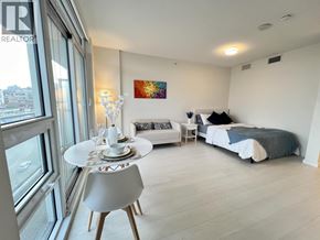 Vancouver apartment for rent - A bedroom with a bed, a couch, a table, and a painting on the wall.