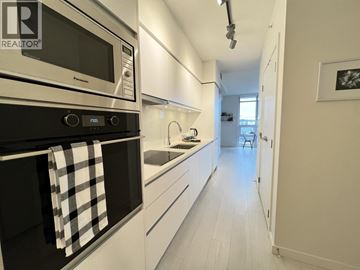 Vancouver apartment for rent - A modern kitchen with white cabinets and a black oven.