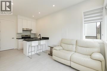 Vancouver apartment for rent - A white living room with a couch and a kitchen area.