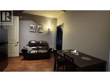 Richmond apartment for rent - A black leather sofa sits in a living room with a wooden table and chairs.