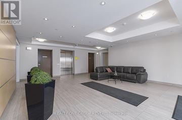 Clarington (Bowmanville) condo for rent - A modern living room with a grey sofa and a black planter.