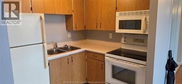 Windsor condo for rent - A kitchen with wooden cabinets and a white refrigerator.