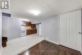 Toronto (Malvern) townhouse for rent - A spacious room with a white door and a kitchen area in the background.