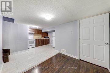 Toronto (Malvern) townhouse for rent - A spacious room with a white door and a kitchen area in the background.