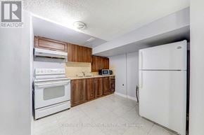 Toronto (Malvern) townhouse for rent - A kitchen with white appliances and wooden cabinets.