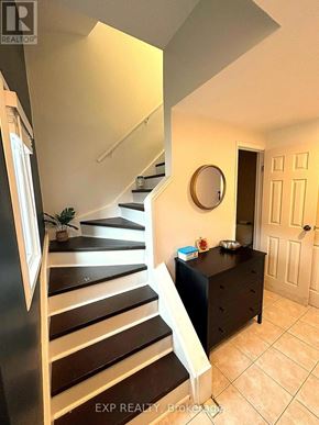 Hamilton (Randall) townhouse for rent - A staircase with a black railing and white steps leads to a landing with a round mirror on the wall.