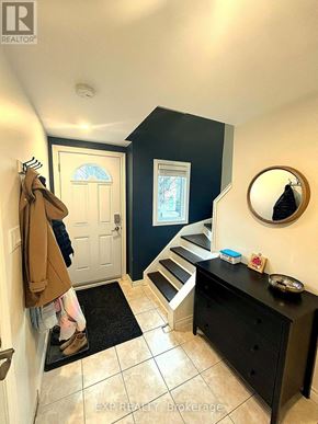 Hamilton (Randall) townhouse for rent - A hallway with a coat hanging on the wall and a mirror above a black dresser.