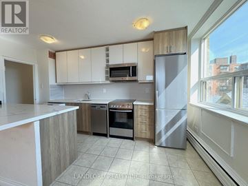 Toronto (South Parkdale) multi-family for rent - A kitchen with white cabinets and a refrigerator.