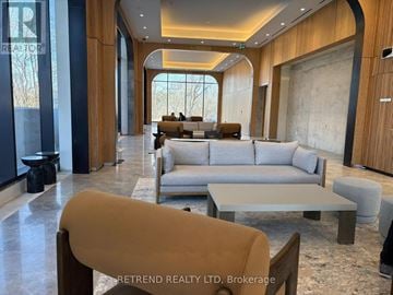 Toronto (Don Valley Village) condo for rent - A spacious living room with a large grey sofa and a wooden floor.