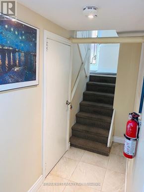 Toronto (Yonge-Eglinton) triplex for rent - A hallway with a staircase and a fire extinguisher on the wall.
