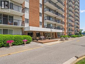 Windsor condo for rent - A multi-story apartment building with a balcony and a small patio area in front.