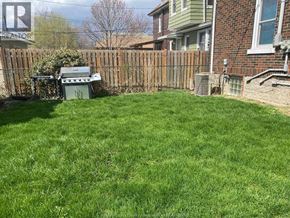Windsor apartment for rent - A backyard with a wooden fence and a green lawn.