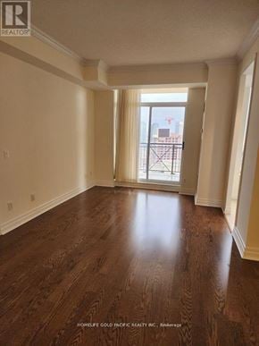 Toronto (Banbury-Don Mills) condo for rent - A room with wooden flooring and a view of a city skyline through a window.