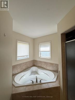 Oshawa (Windfields) apartment for rent - A bathroom with a tub and two windows.