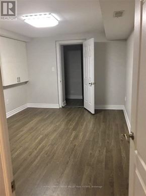 Brampton (Northwest Brampton) apartment for rent - A room with wooden flooring and white walls, with a door at the end of the room.
