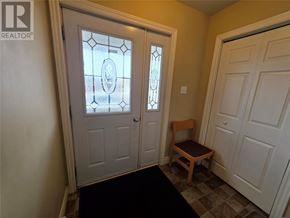 Labrador City apartment for rent - A white door with a glass window and a wooden chair in front of it.