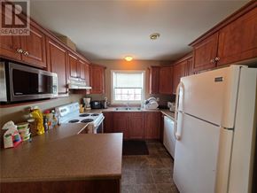 Labrador City apartment for rent - A kitchen with brown cabinets and a white refrigerator.