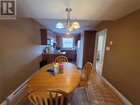 Labrador City apartment for rent - A wooden dining table with chairs and a chandelier in a room.