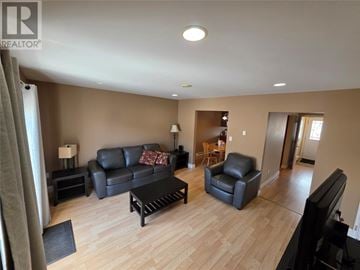 Labrador City apartment for rent - A living room with a black leather couch and a wooden coffee table.