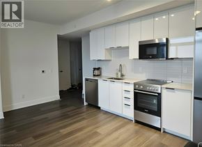 Kitchener condo for rent - A modern kitchen with white cabinets and stainless steel appliances.