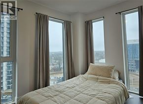 Kitchener condo for rent - A bedroom with a large bed and a view of the city.