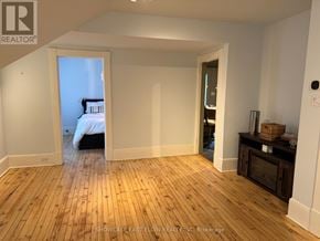 Aylmer multi-family for rent - A room with wooden flooring and white walls, with a bed visible through an open door.