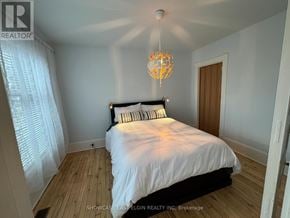 Aylmer multi-family for rent - A bedroom with a bed, a chandelier, and a window with curtains.