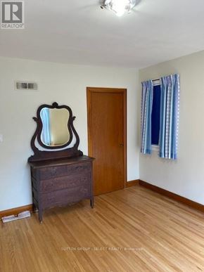 London North (North K) triplex for rent - A room with a wooden floor, a wooden door, a wooden dresser with a mirror and a window with blue curtains.