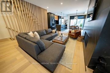 Ottawa apartment for rent - A modern living room with a grey sofa and a wooden wall panel.