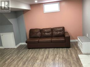 Brampton (Sandringham-Wellington) apartment for rent - A brown leather couch sits in a room with wooden flooring and a white cabinet.