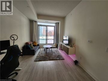 Kitchener condo for rent - A living room with a black chair and a small table.