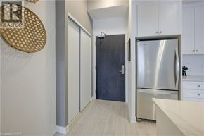Kitchener condo for rent - A living room with a black chair and a desk with a computer.