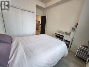 Kitchener condo for rent - A bedroom with a bed, desk, and chair.