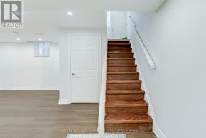 Toronto (Rouge) apartment for rent - A white door is in a hallway with a wooden staircase.