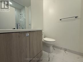 Vaughan (Vaughan Corporate Centre) condo for rent - A white toilet sits in a bathroom with a wooden cabinet and a glass shower door.