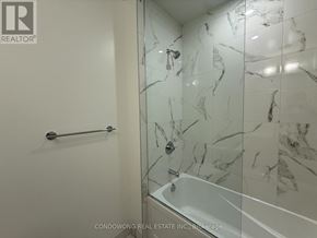 Vaughan (Vaughan Corporate Centre) condo for rent - A white marble tiled shower with a glass door and a black grab bar.