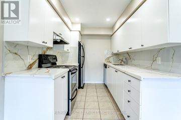 Mississauga (Churchill Meadows) townhouse for rent - A white kitchen with a marble counter top and a refrigerator.